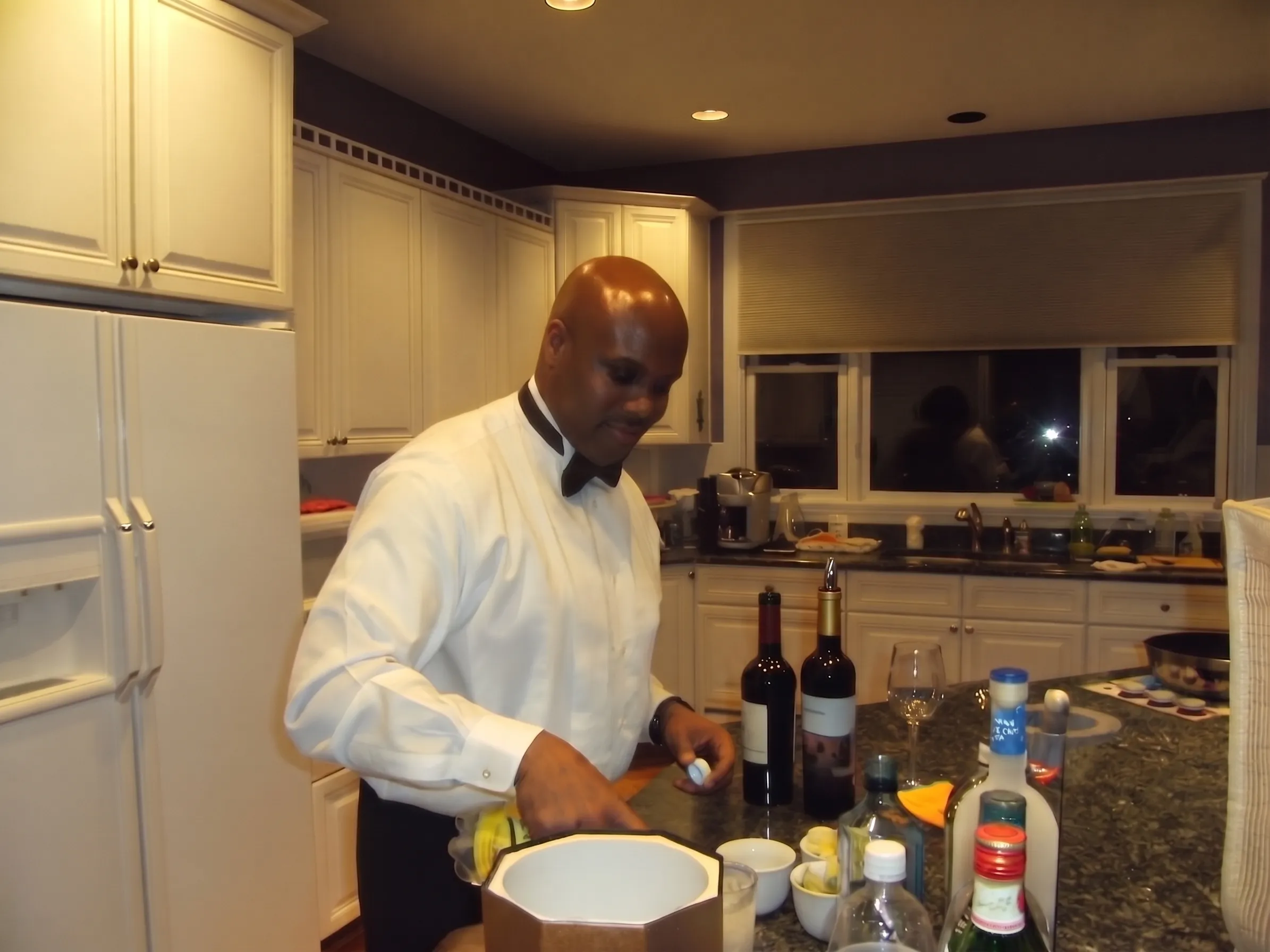 Founder Eric Chapman in a tuxedo shirt and bow tie mixing drinks at a home party bar